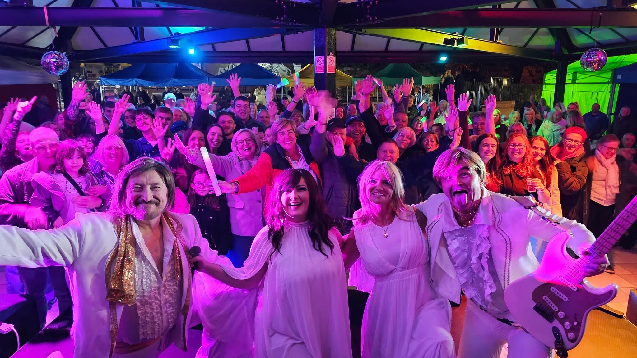 An ABBA tribute band celebrating on stage with a cheering crowd at The Corner in Darvel